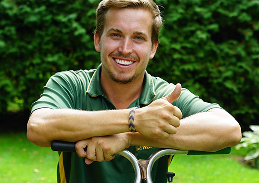 Weed Man technician leaning on fertilizer spreader